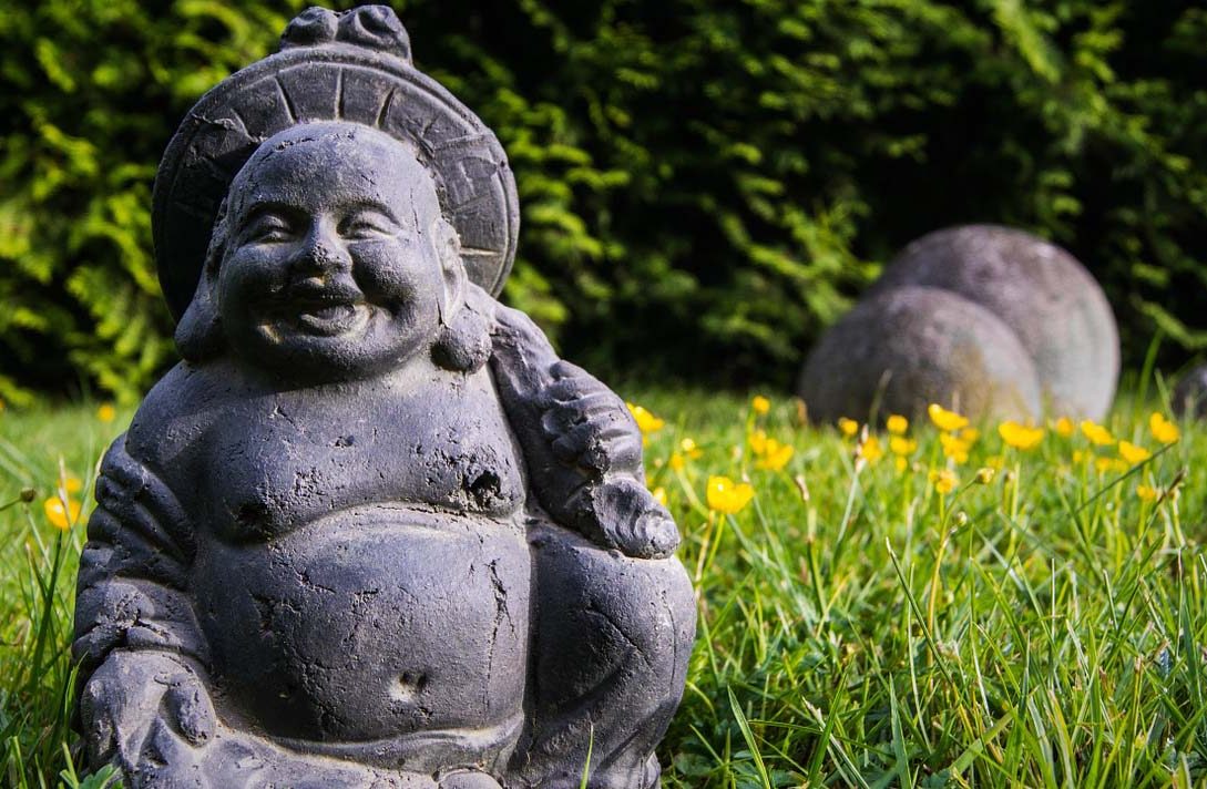 Smiling Buddha in Grass with Yellow Flowers