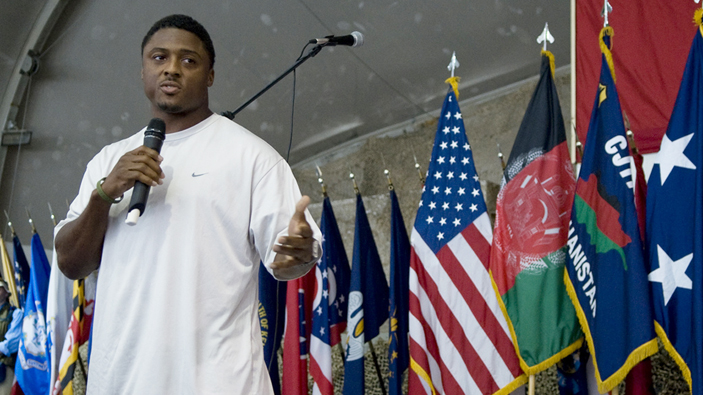 Warrick Dunn talking in front of flags