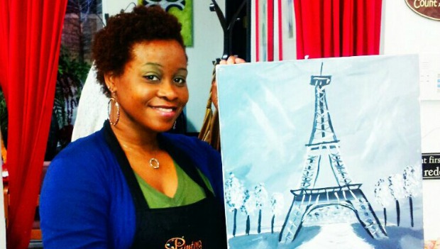 Woman holding up a painting of the Eiffel Tower