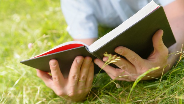 Man reading a book in the grass