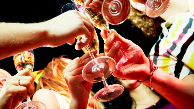 People clinking wine glasses at a party.
