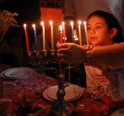 A child lighting a menorah.