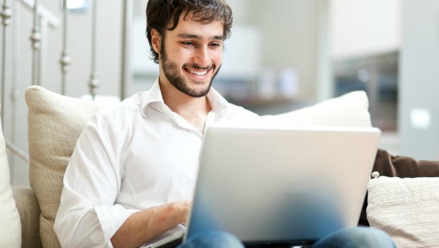 Attractive bearded man checks his social media on a laptop computer.