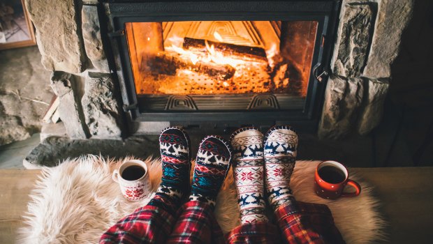 Two people warming their feet in front of a cozy fire.