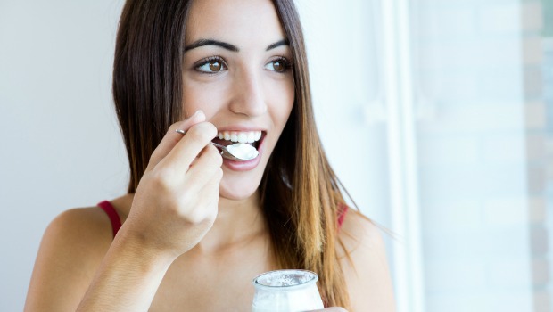 Woman eating spoonful of yogurt.
