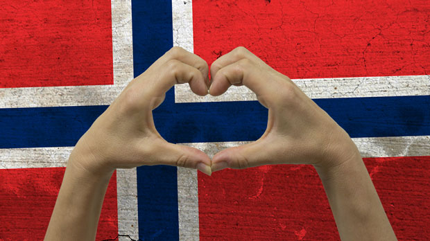 The Norwegian flag with hands in a heart-shape in front of it.