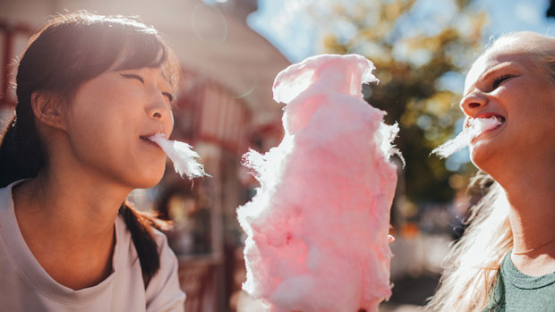 Two young women eating cotton candy.