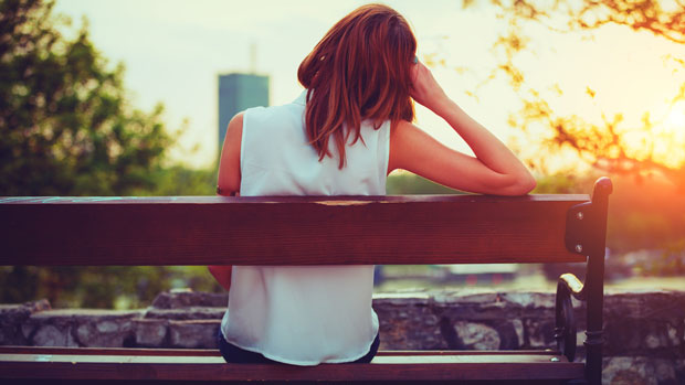 Pensive woman sitting on a bench.