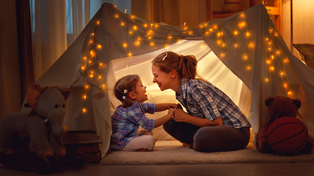 Mom and daughter in a tent indoors.
