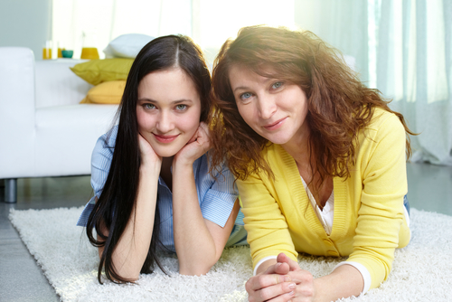 Restful mother and teen-age daughter lying on the floor at home, self-esteem