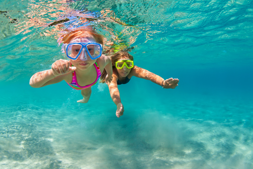 Happy family - mother with baby girl dive underwater with fun in sea pool.