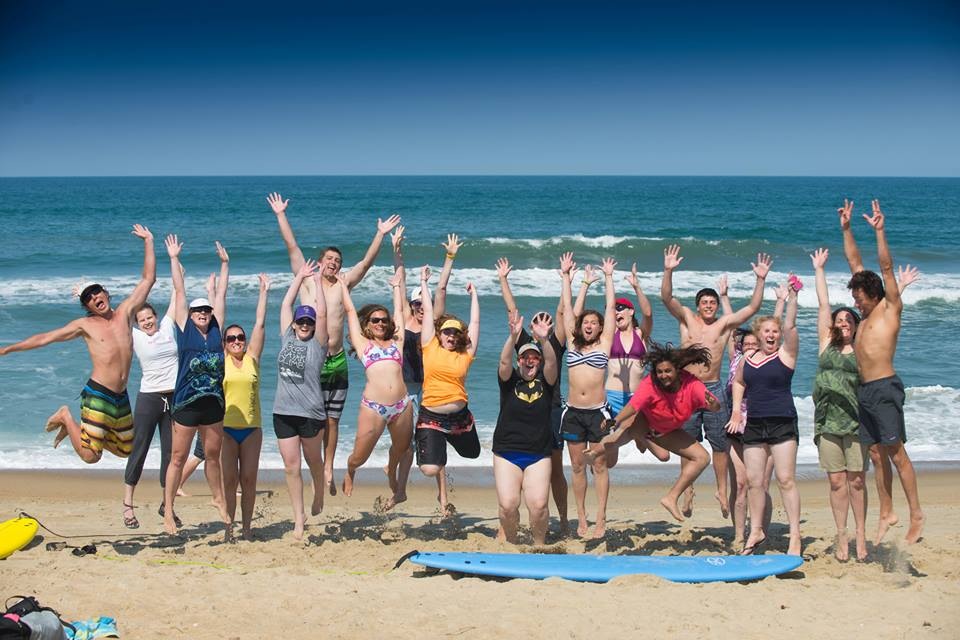 Young adult cancer fighters and survivors jumping on a beach