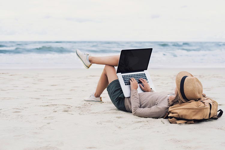 Young woman using laptop computer on a beach.