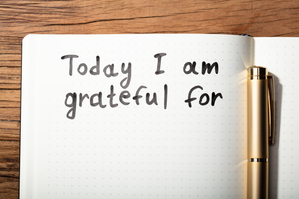 Close-up Of Gratitude Word With Pen On Notebook Over Wooden Desk