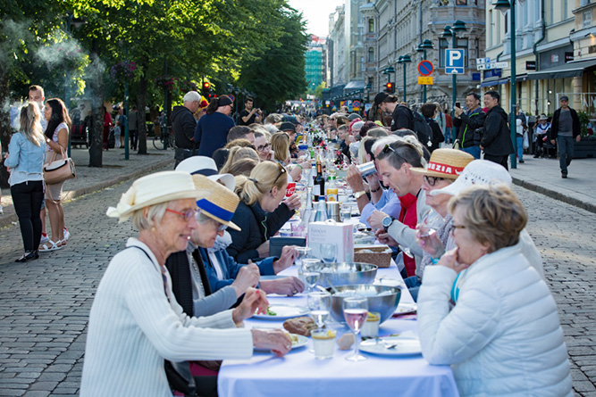 Long table with  people eating and drinking together in Finland