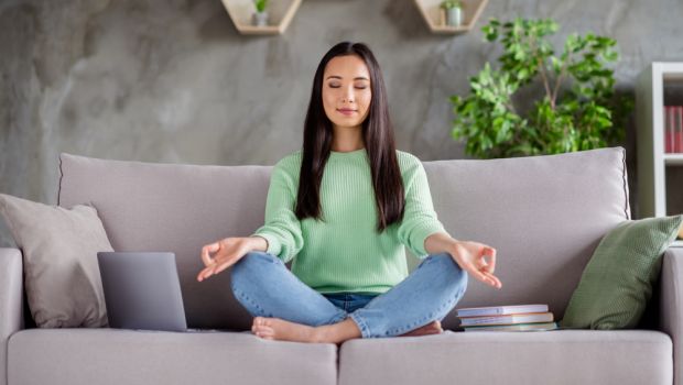 A woman meditating on a couch.