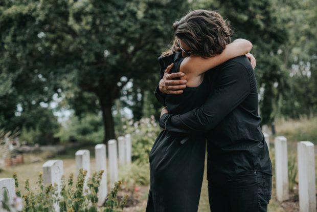 Husband trying to comfort his wife at a graveyard