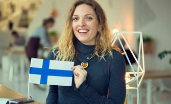 Portrait Scandinavian woman holds the flag of Finland in the background on the premises of the cafe.