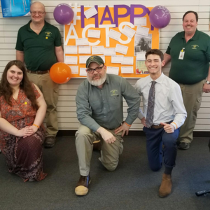 A group of coworkers standing in front of their Work Happiness Wall.