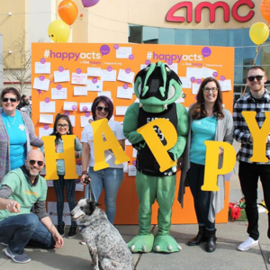 A group of people standing in front of a Happiness Wall in their community.