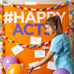 A woman decorating an orange Happiness Wall.